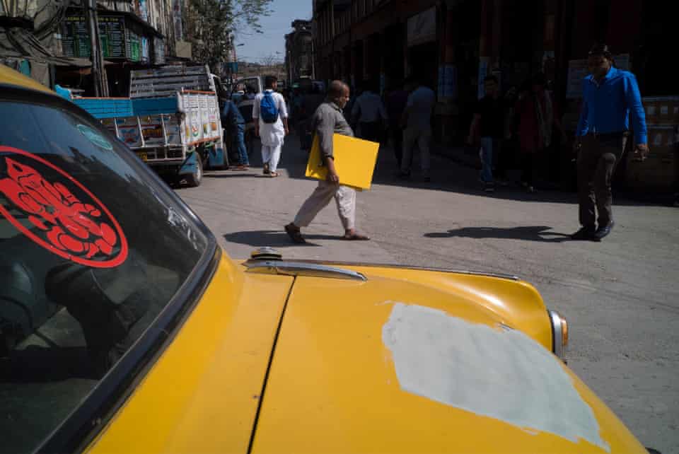 The yellow board that the man holds here aligns with the missing paint of the car, creating an optical illusion that blurs the barrier between the two.